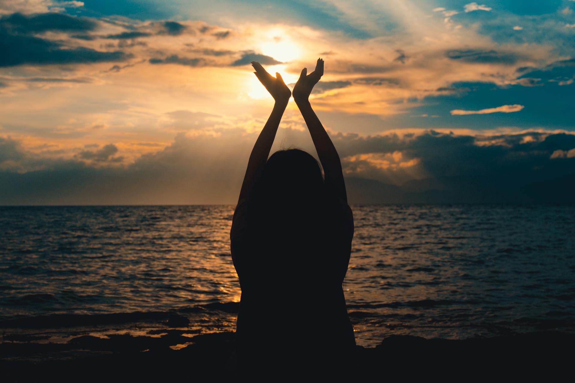 femme épanouie au bord de la plage avec un coucher de soleil